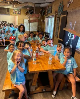 A group of children cheering together around a long table