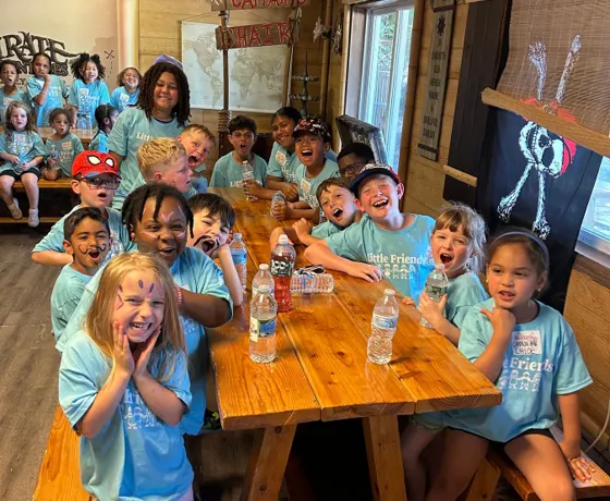 A large group of children cheering around a table