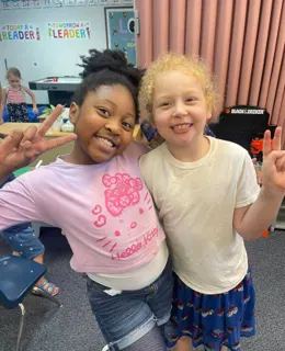 Two classmates smiling and giving peace signs